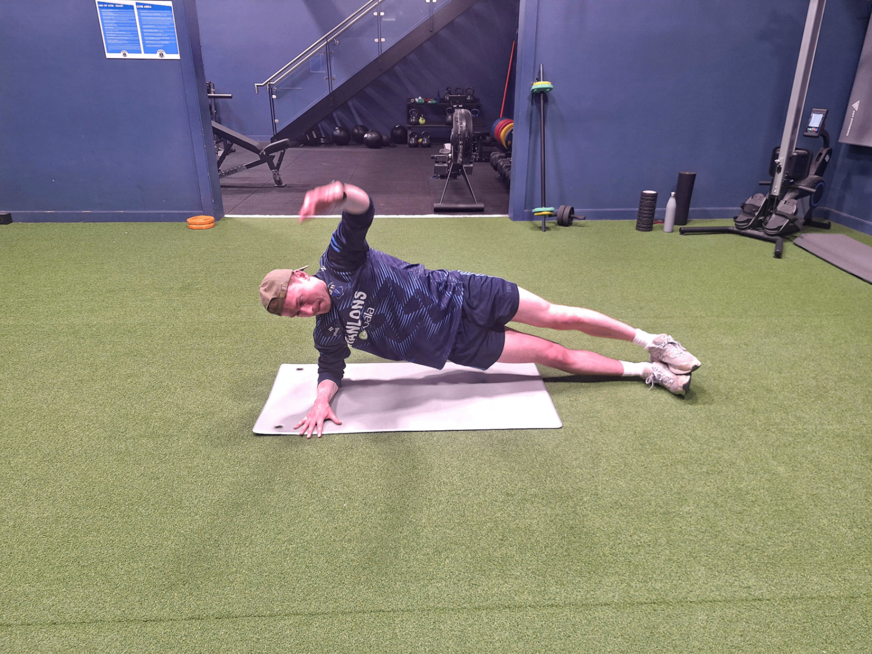 Athlete performing a side plank rotation in the gym