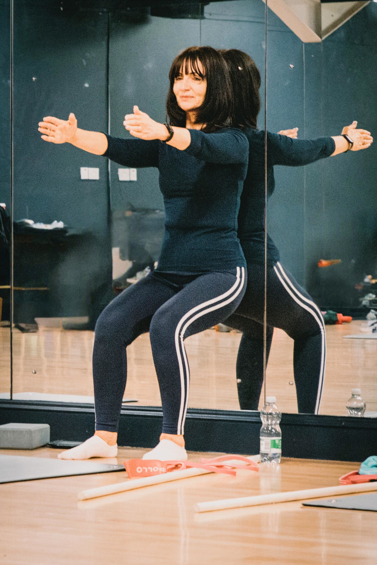 Client practising squat mechanics in front of the studio mirror wall