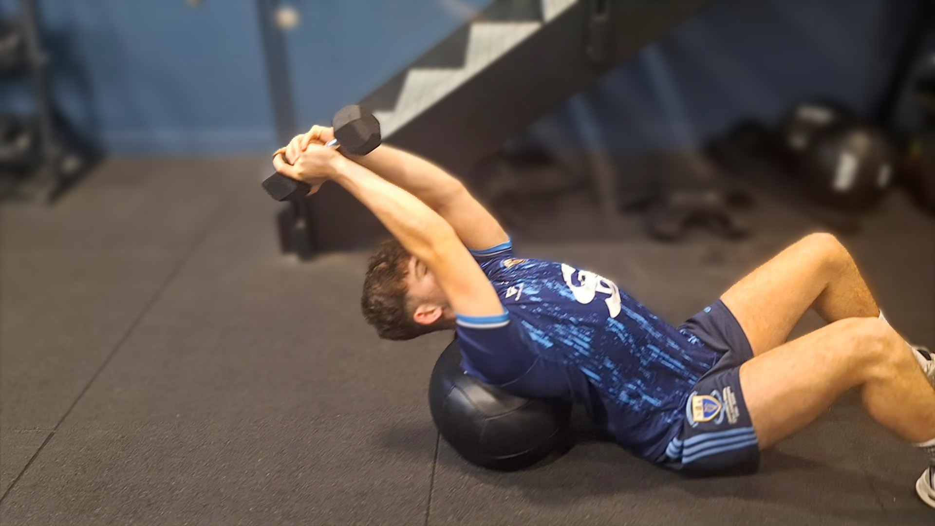 Athlete performing a dumbbell pullover on a stability ball