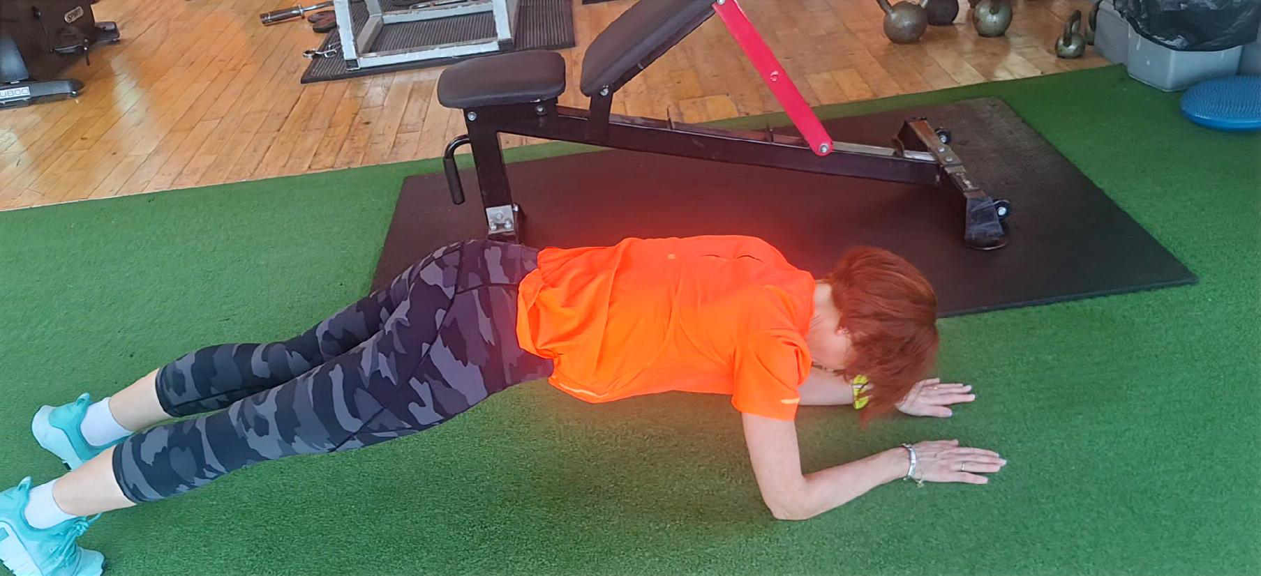 Client holding a forearm plank on the gym floor
