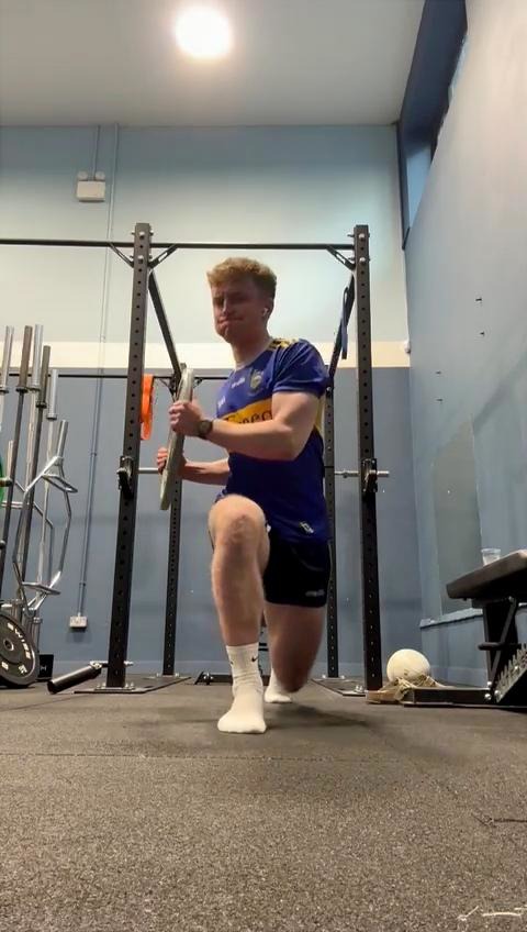 Athlete performing a loaded half-kneeling exercise