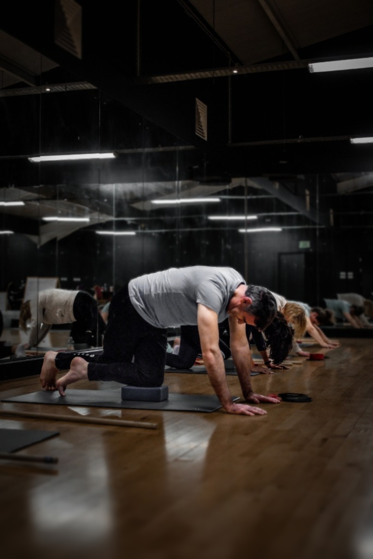 Clients performing mobility work on mats in the dark studio